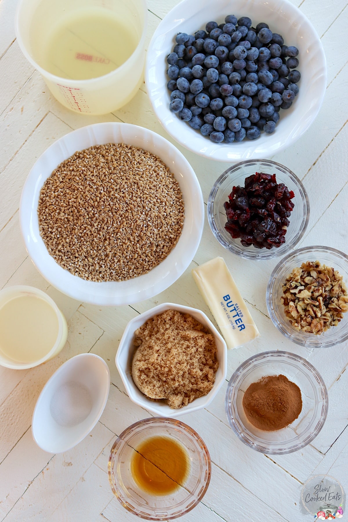 Ingredients needed for making slow cooker steel cut oats on a white wooden board.