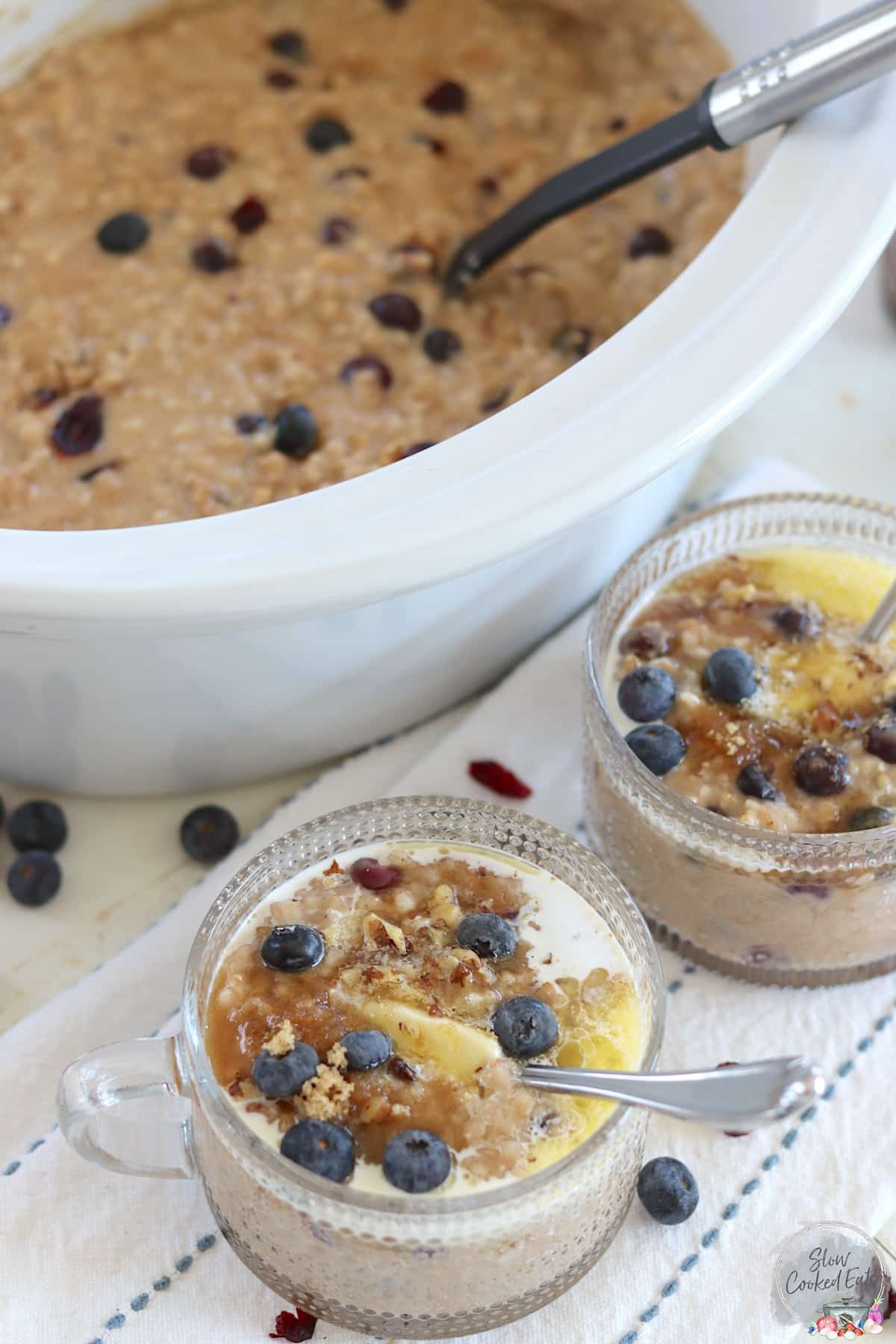 Two clear bowls with handles served with slow cooker steel cut oats with blueberries.