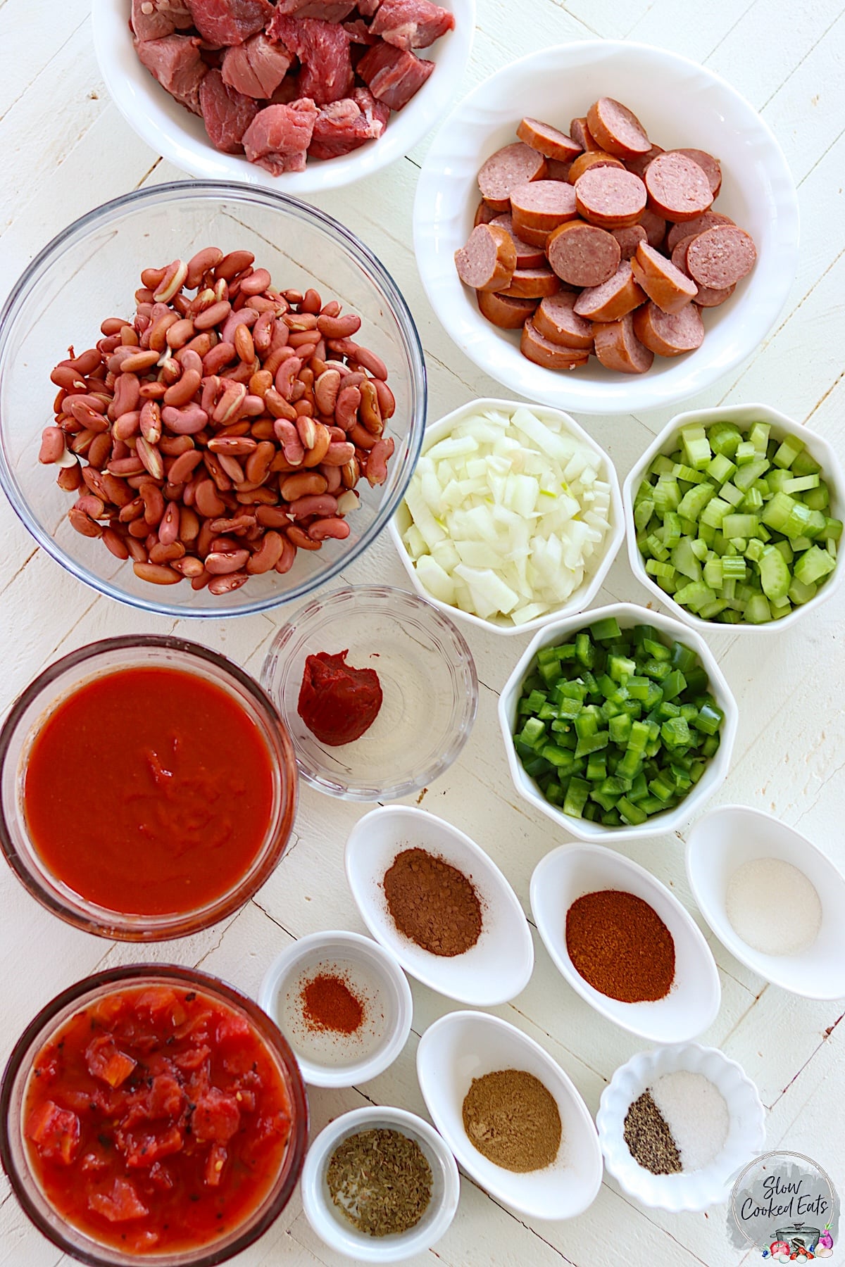Ingredients needed for making crock pot chili on a white wooden board.