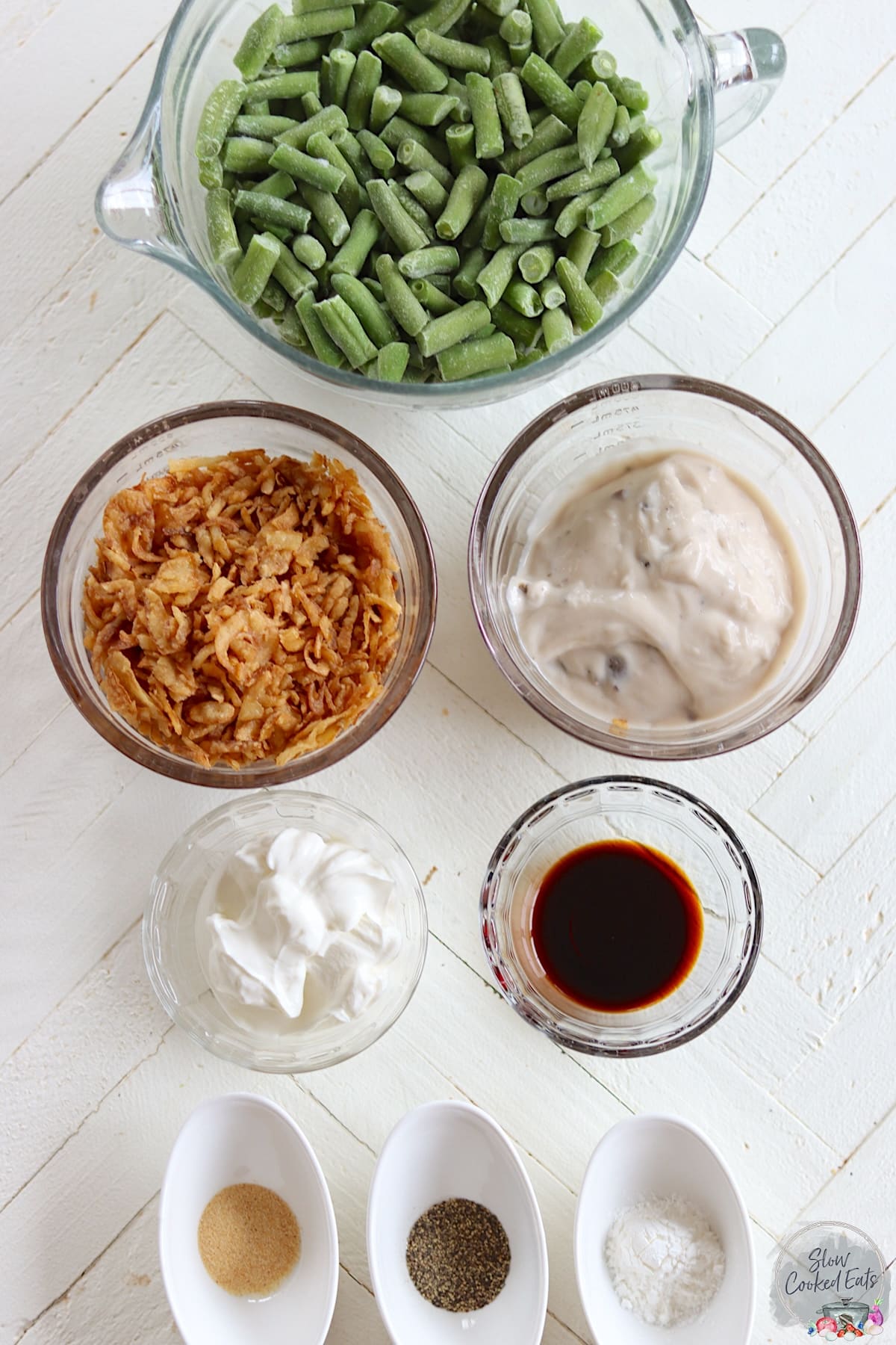 Ingredients needed for making crockpot green bean casserole on a white wooden board.