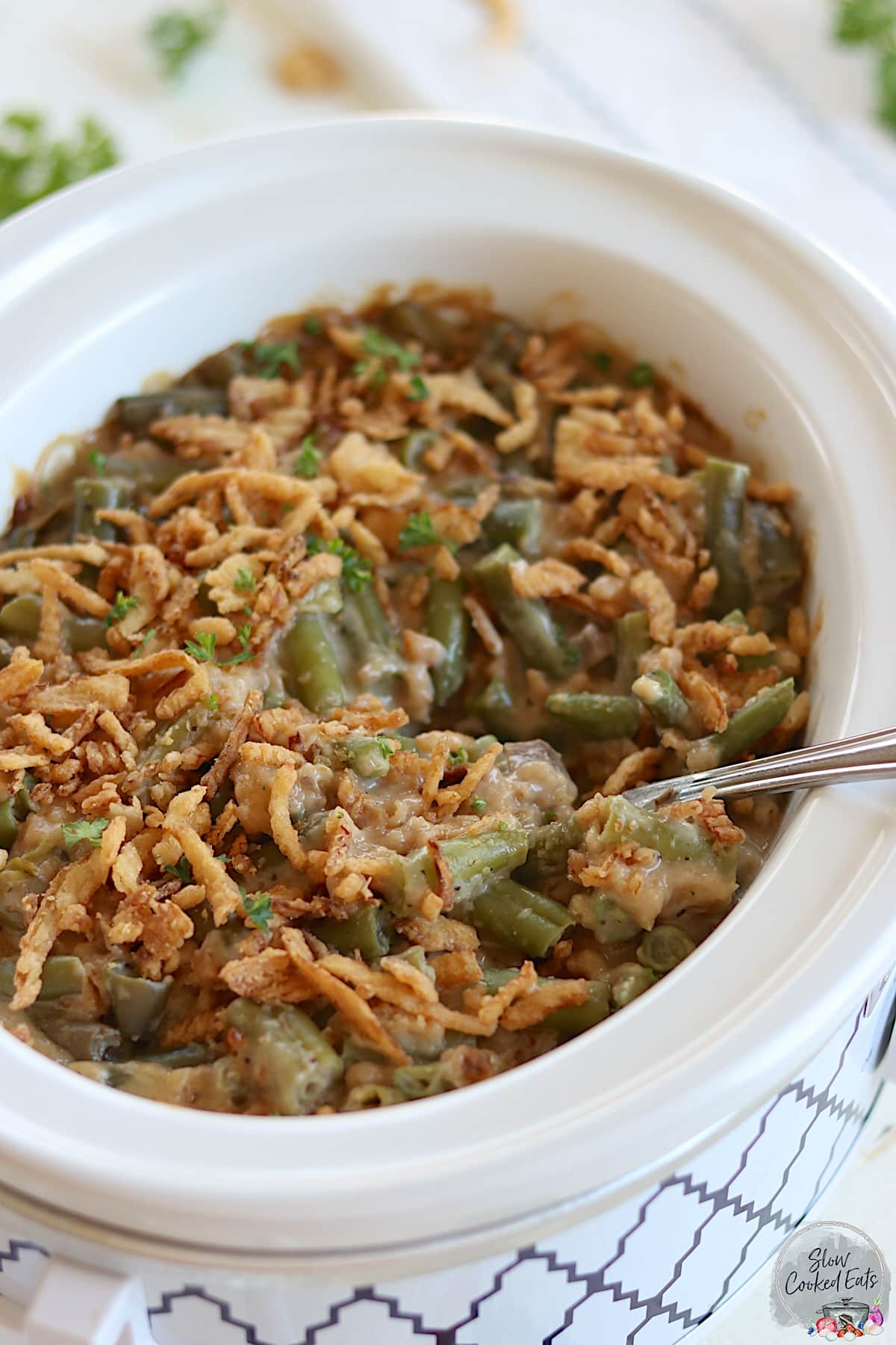 Crockpot green bean casserole topped with french fried onions and fresh parsley.
