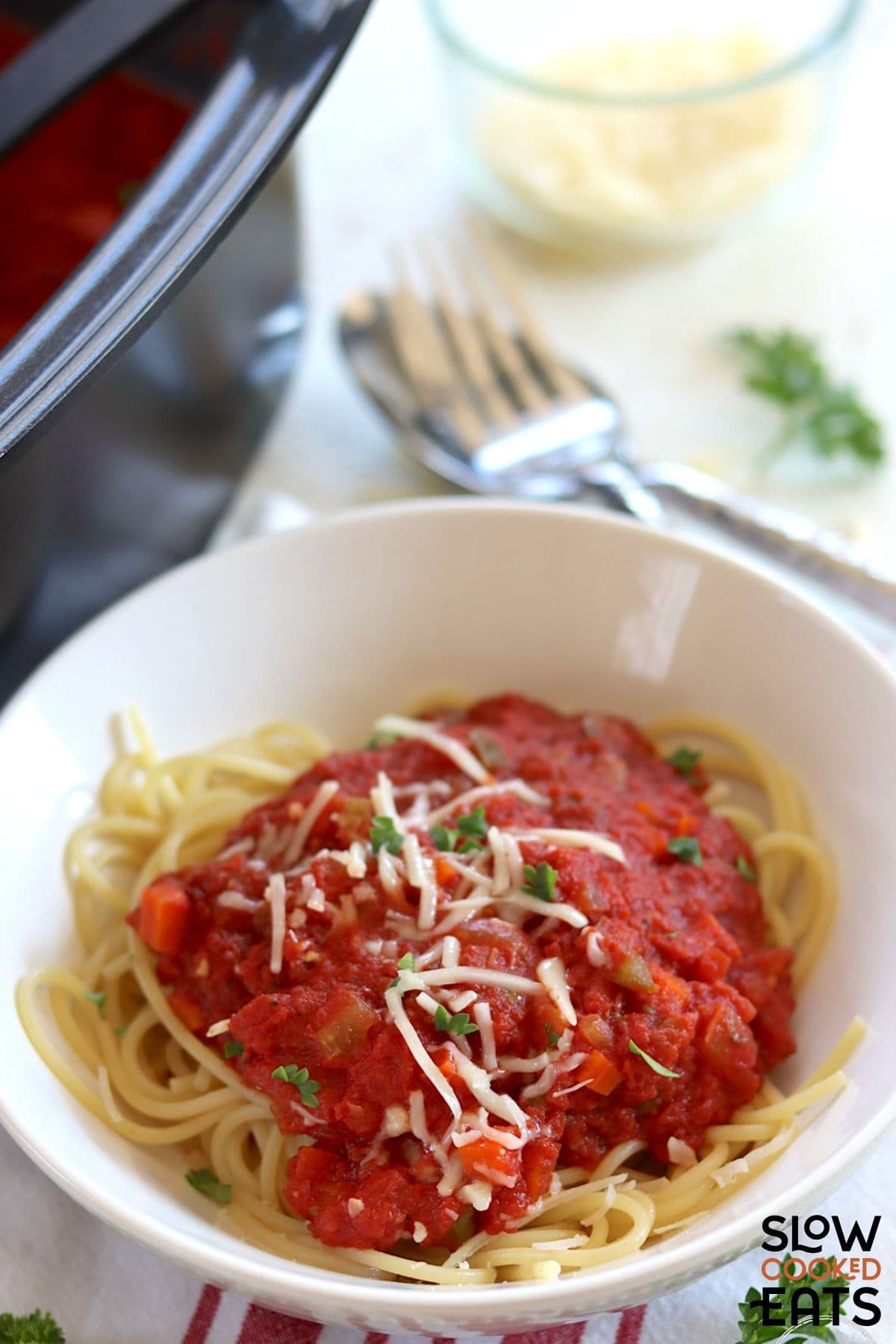 Crockpot marinara sauce served over noodles with the slow cooker behind it.