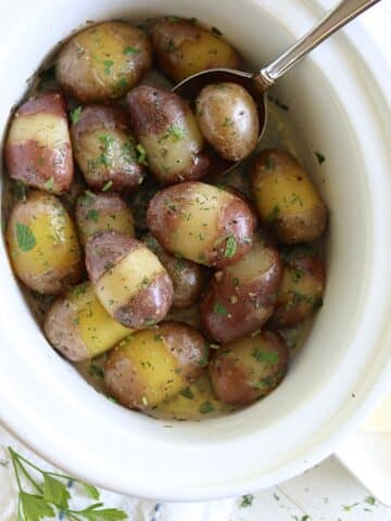 Crockpot baby red potatoes with butter and fresh herbs.