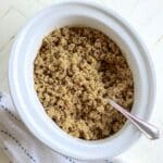 Fully cooked slow cooker quinoa in a white oval crock.