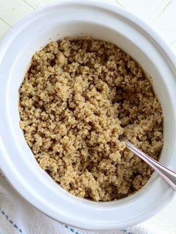 Fully cooked slow cooker quinoa in a white oval crock.