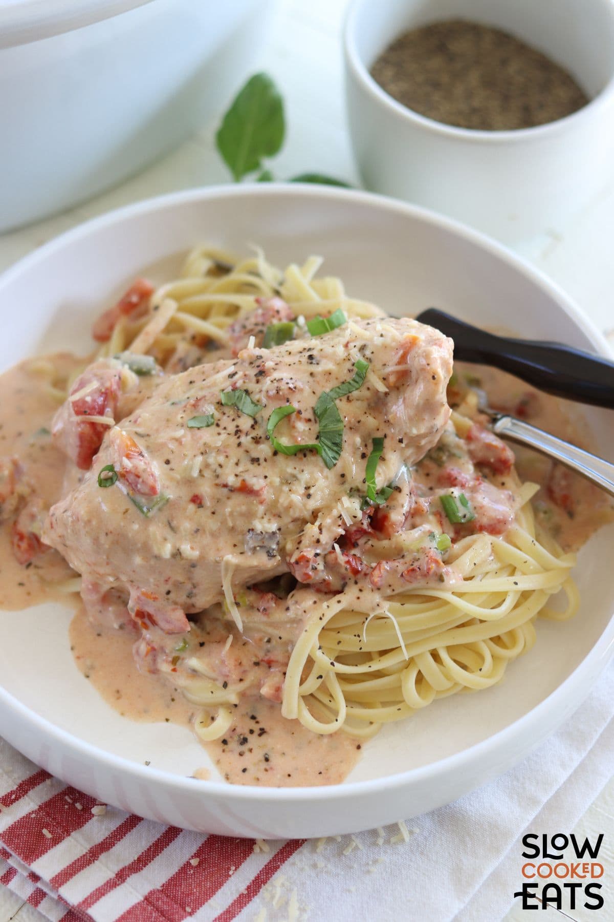 A plate of crockpot marry me chicken served over pasta.