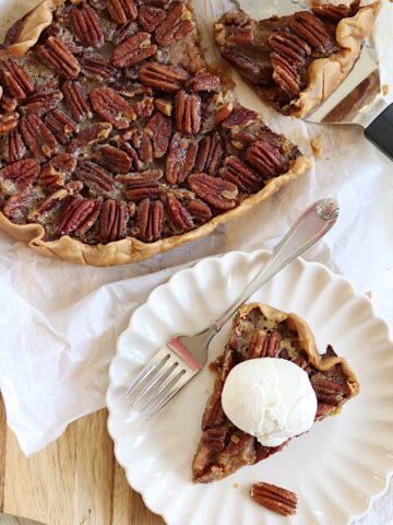 A slice of crockpot peca pie with vanilla ice cream on a scalloped plate.