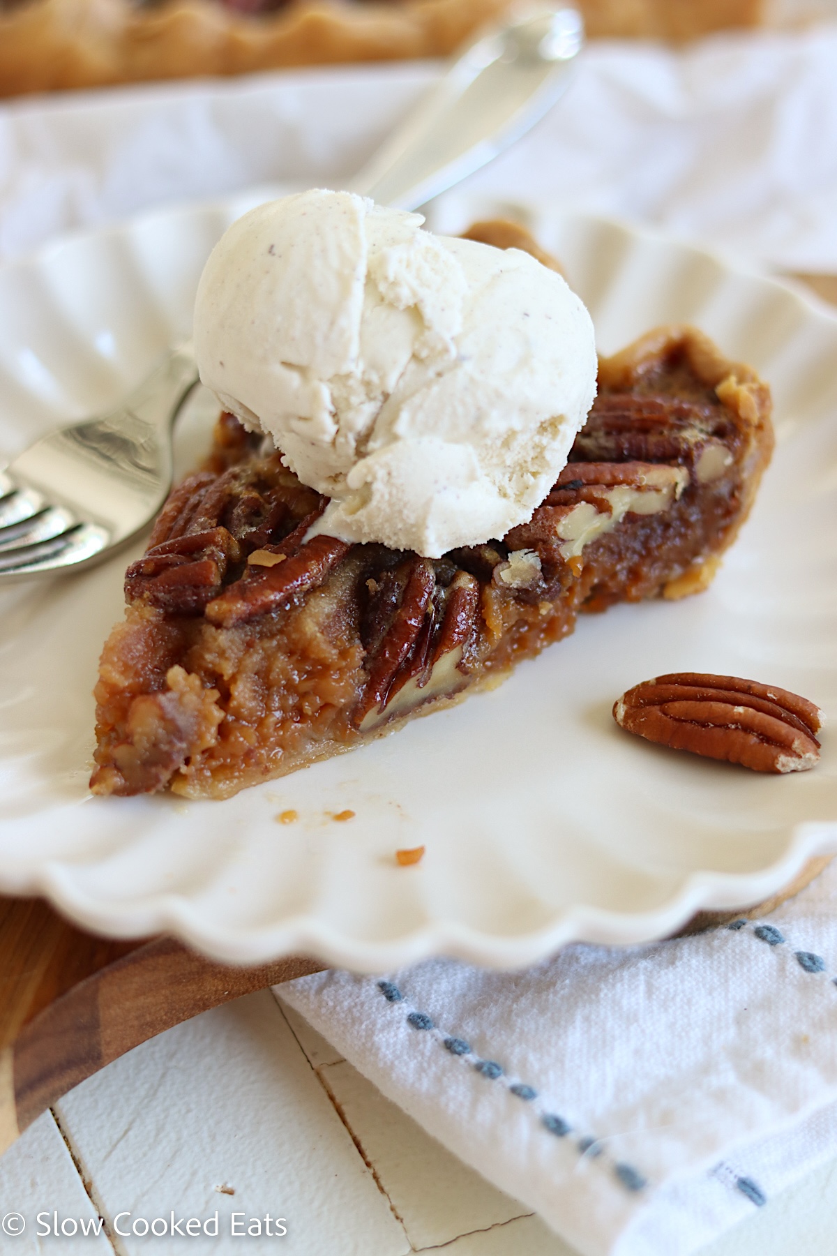 A slice of pecan pie with a scoop of vanilla bean ice cream.