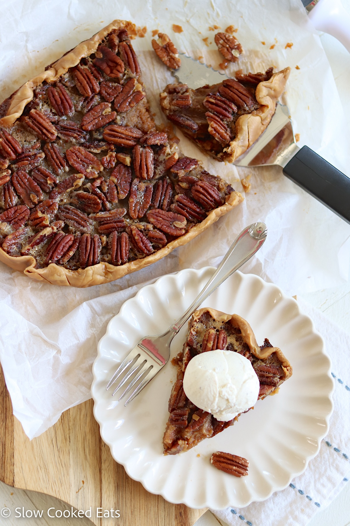 A pecan slab pie and a slice of the pie on the side with vanilla ice cream.