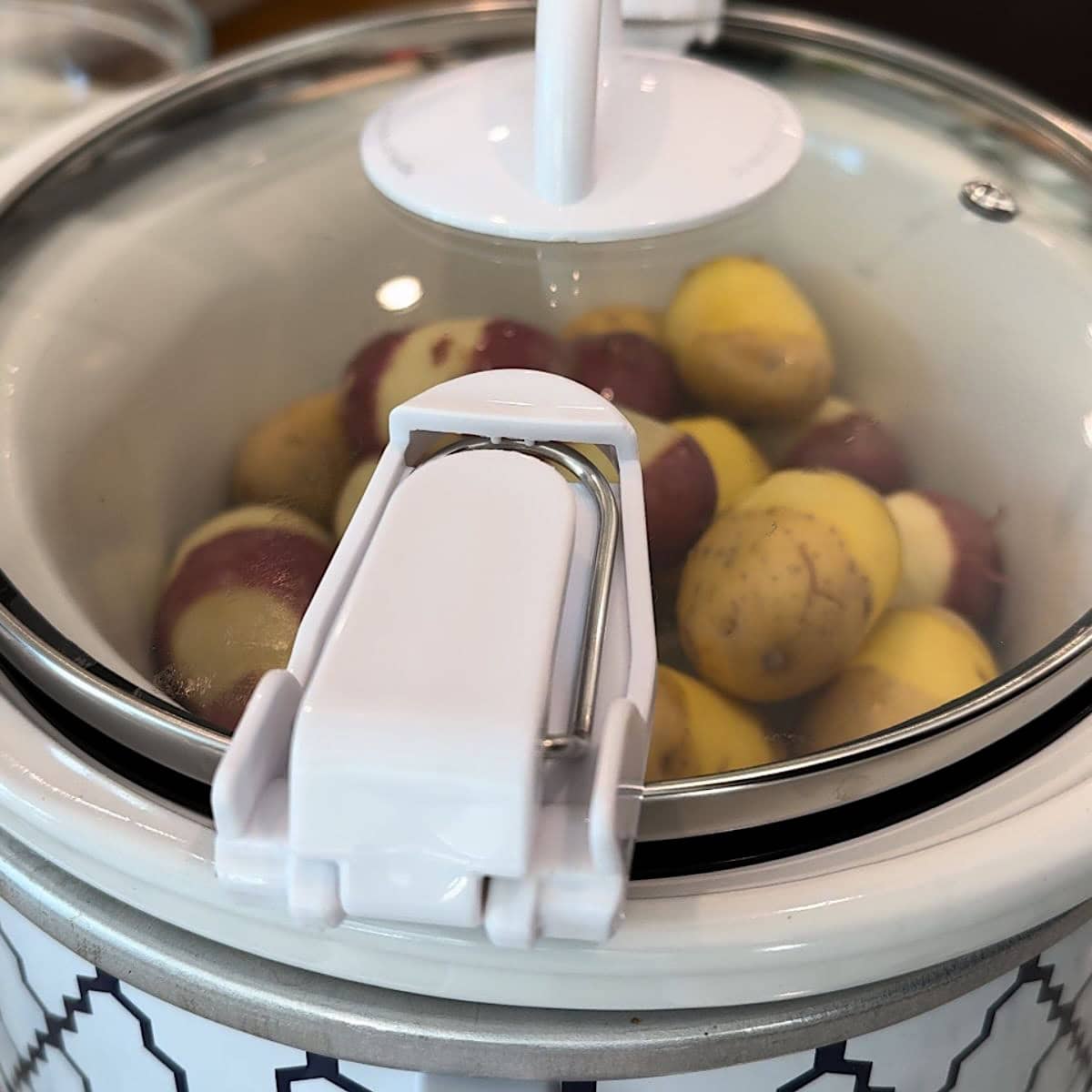 Placing the lid on the crockpot baby potatoes.