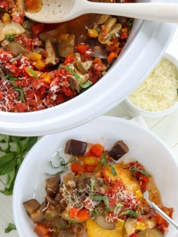 A white oval crockpot and white serving bowl of ratatouille slow cooker recipe.