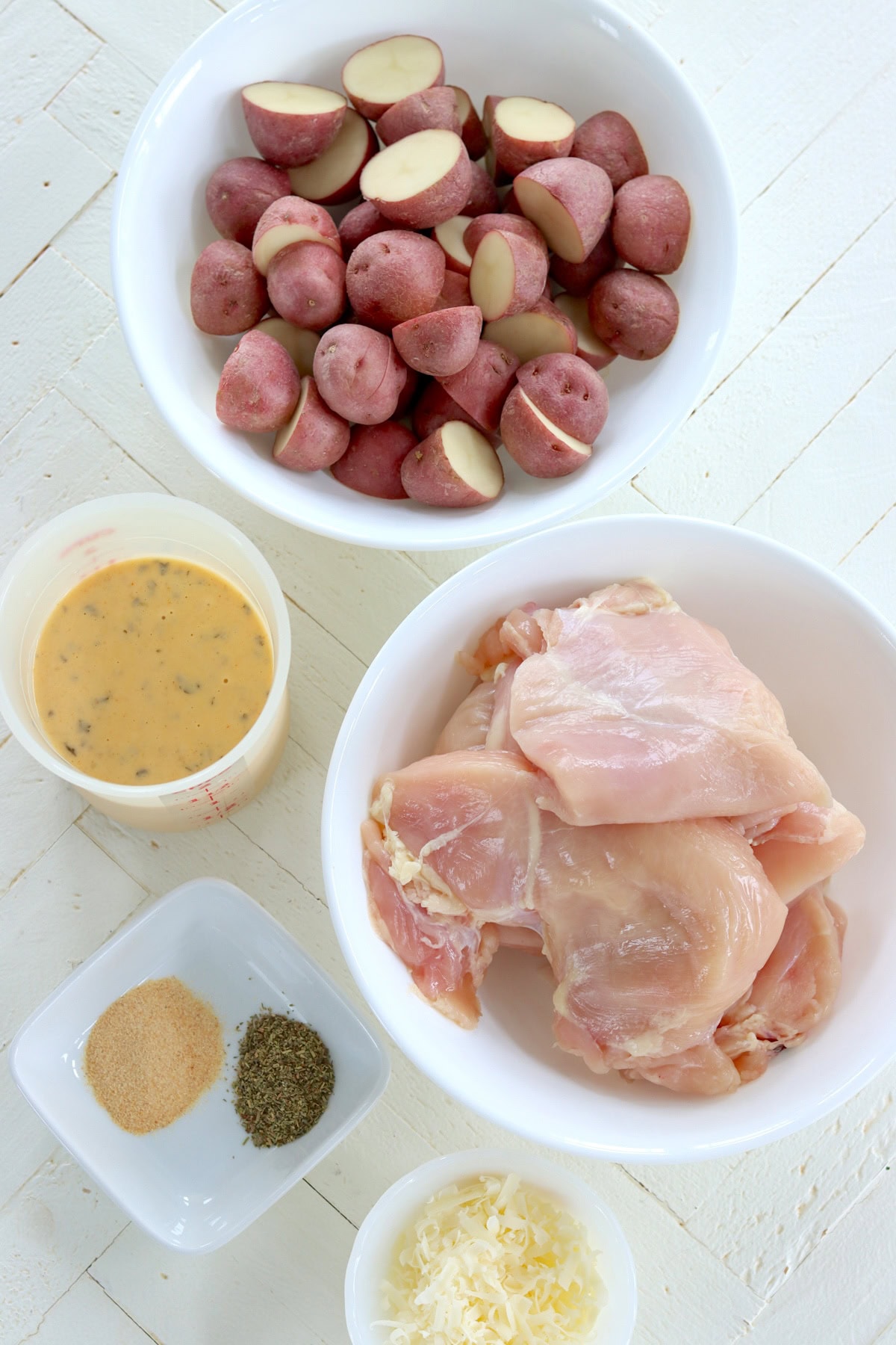 All the ingredient needed for making chicken and potatoes slow cooker recipe on a white wooden board.