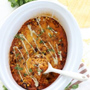Crockpot chicken enchilada casserole in a white slow cooker.