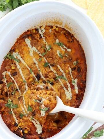 Crockpot chicken enchilada casserole in a white slow cooker.
