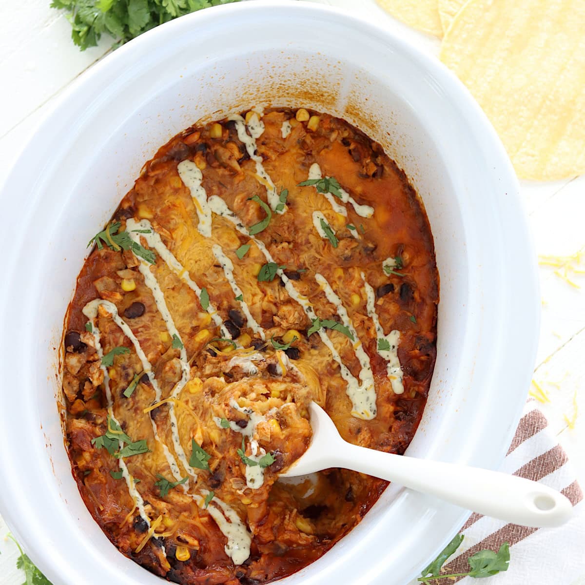 Crockpot chicken enchilada casserole in a white slow cooker.