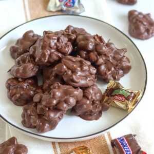 Crockpot chocolate candy bar bites on a white plate with mini chocolate bars.