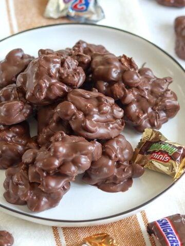 Crockpot chocolate candy bar bites on a white plate with mini chocolate bars.