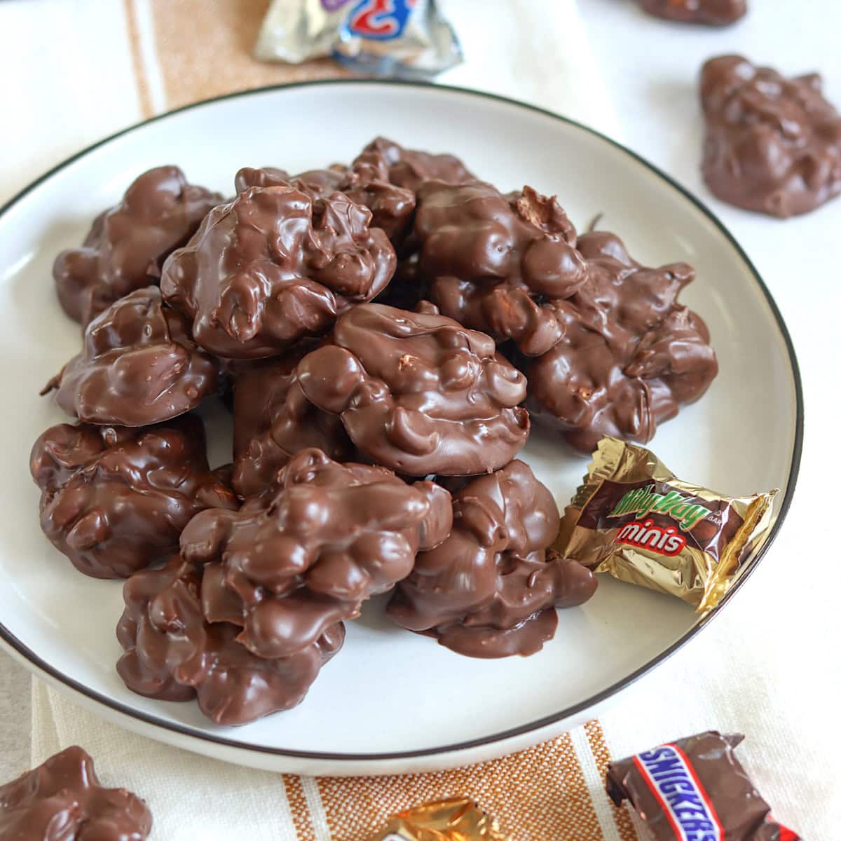 Crockpot chocolate candy bar bites on a white plate with mini chocolate bars.