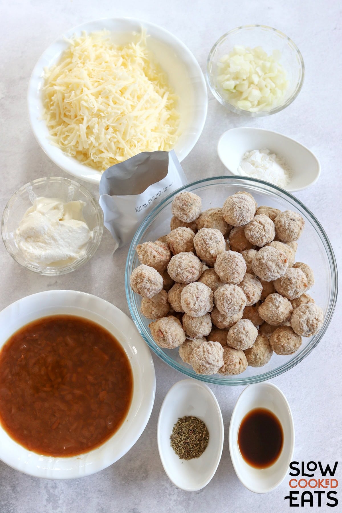 French onion meatballs crockpot recipe ingredients on a white board.