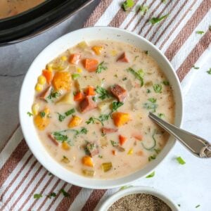 Crockpot ham and potato soup in a white bowl with a spoon.