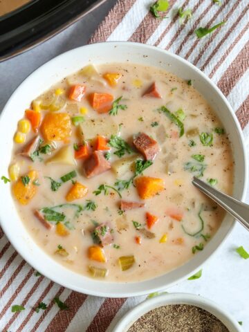 Crockpot ham and potato soup in a white bowl with a spoon.