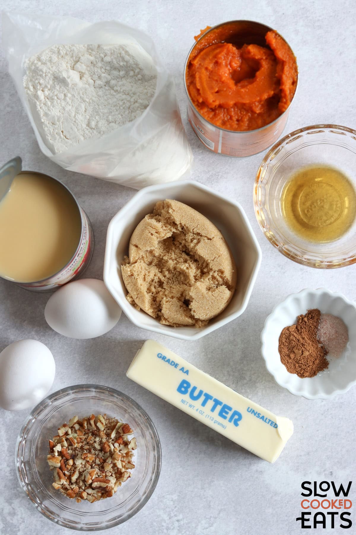 Ingredients needed for making crockpot pumpkin dump cake on a white board.