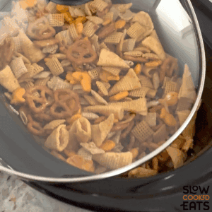 Covering the black crockpot and cooking parmesan ranch slow cooker Chex mix.