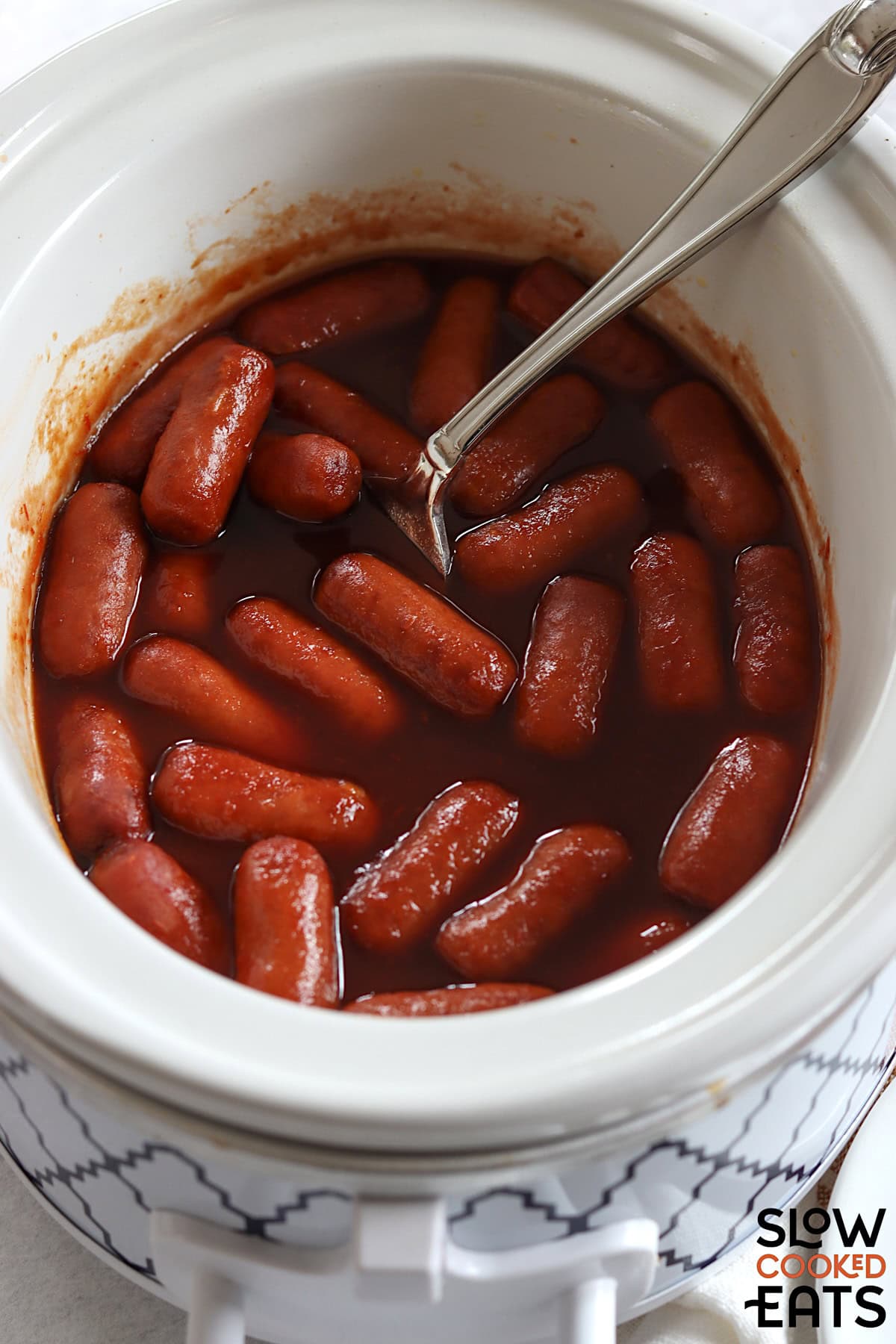 Crockpot little smokies grape jelly recipe in a white oval slow cooker.