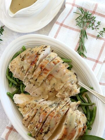 Herb butter slow cooker turkey breast sliced and served on a white plate and silver fork.