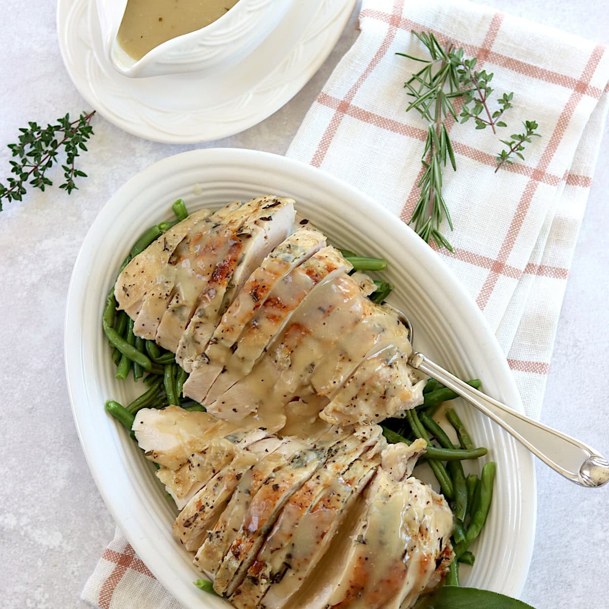 Herb butter slow cooker turkey breast sliced and served on a white plate and silver fork.