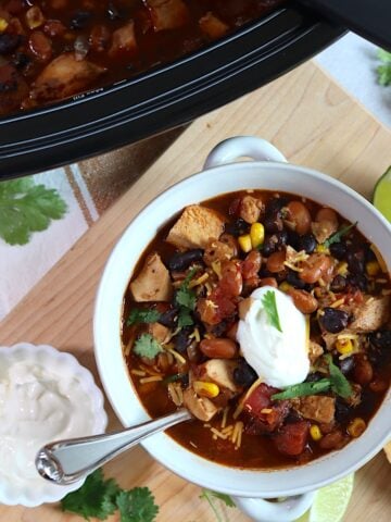 Leftover turkey chili crockpot recipe served in a white bowl and silver spoon.