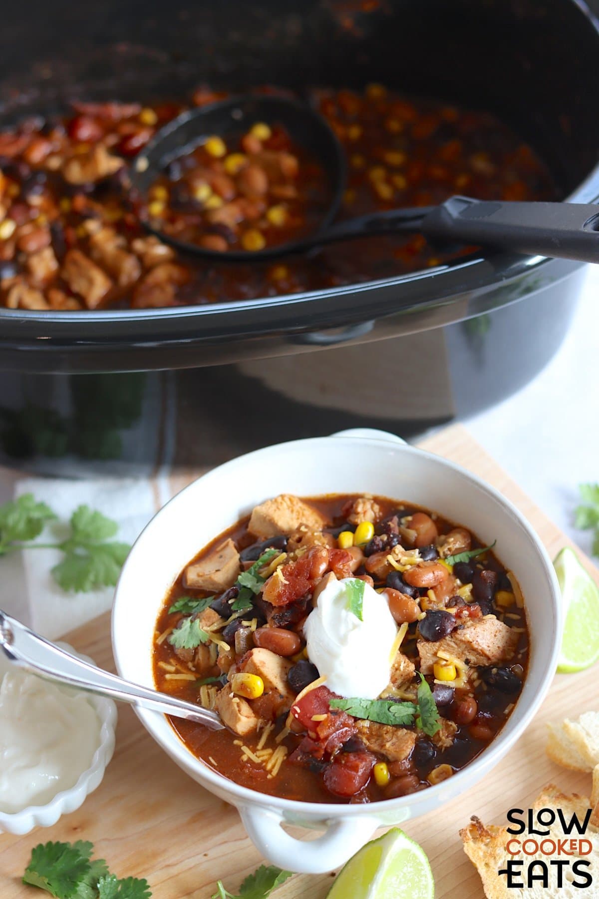 A white bowl filled with leftover turkey chili crockpot recipe and silver spoon.