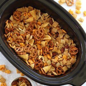 A black oval crockpot filled with parmesan ranch slow cooker Chex mix.