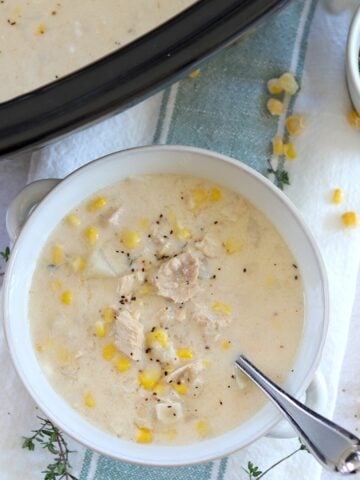 Leftover turkey corn chowder crockpot recipe served in a white bowl and silver spoon.