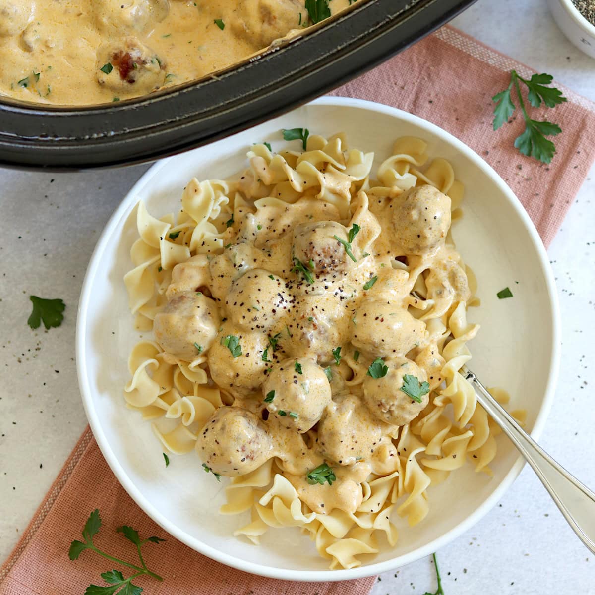 Swedish meatballs crockpot recipe served in a white bowl and silver fork.