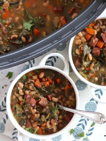 Crockpot Ham and Black Eyed Pea Soup with Collard Greens served in small white crocks and a silver silver spoon.
