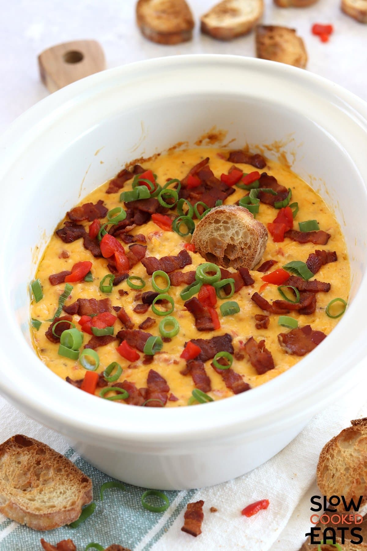 A white oval slow cooker filled with hot pimento cheese dip crockpot recipe.