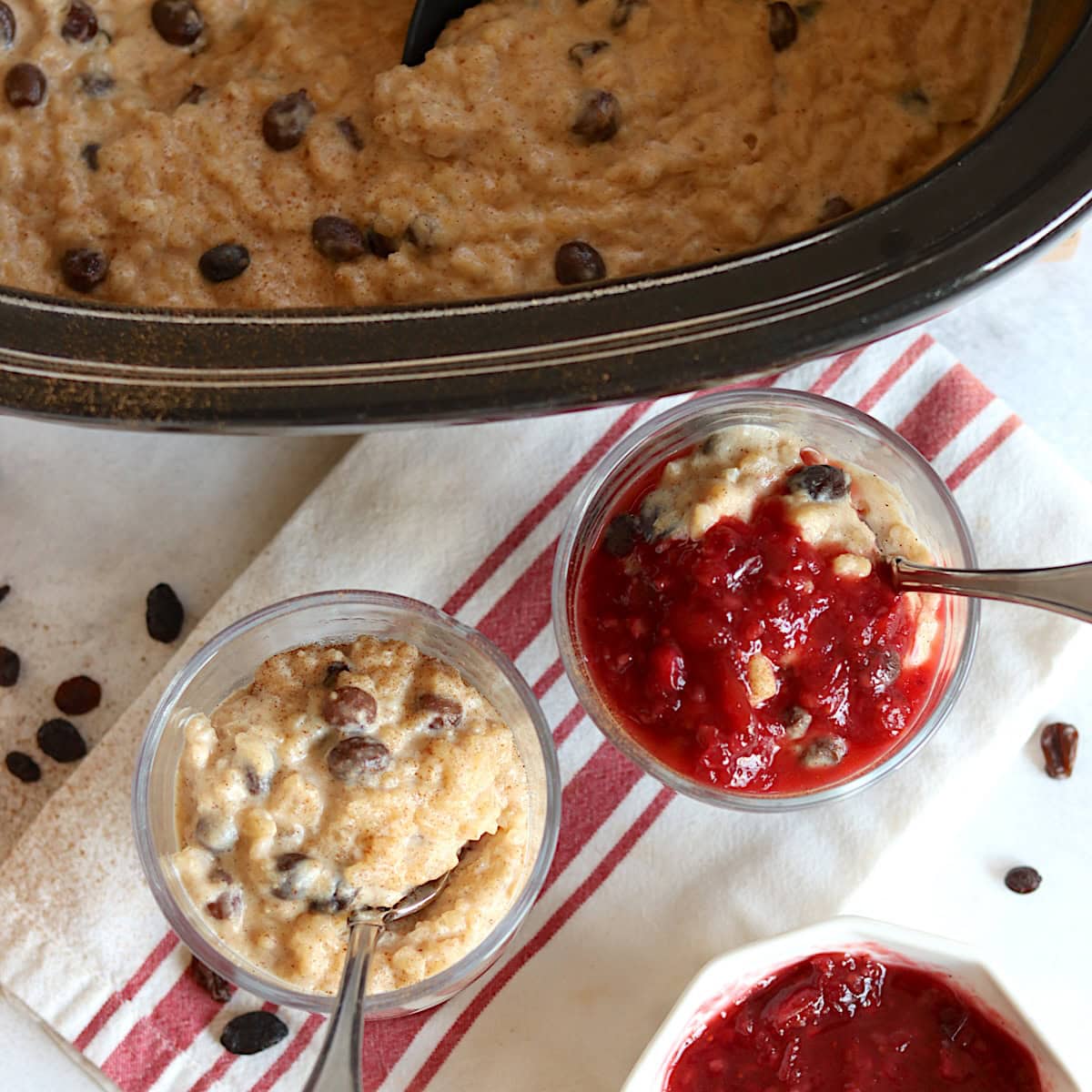 Serving crockpot rice pudding in two glasses and silver spoons.
