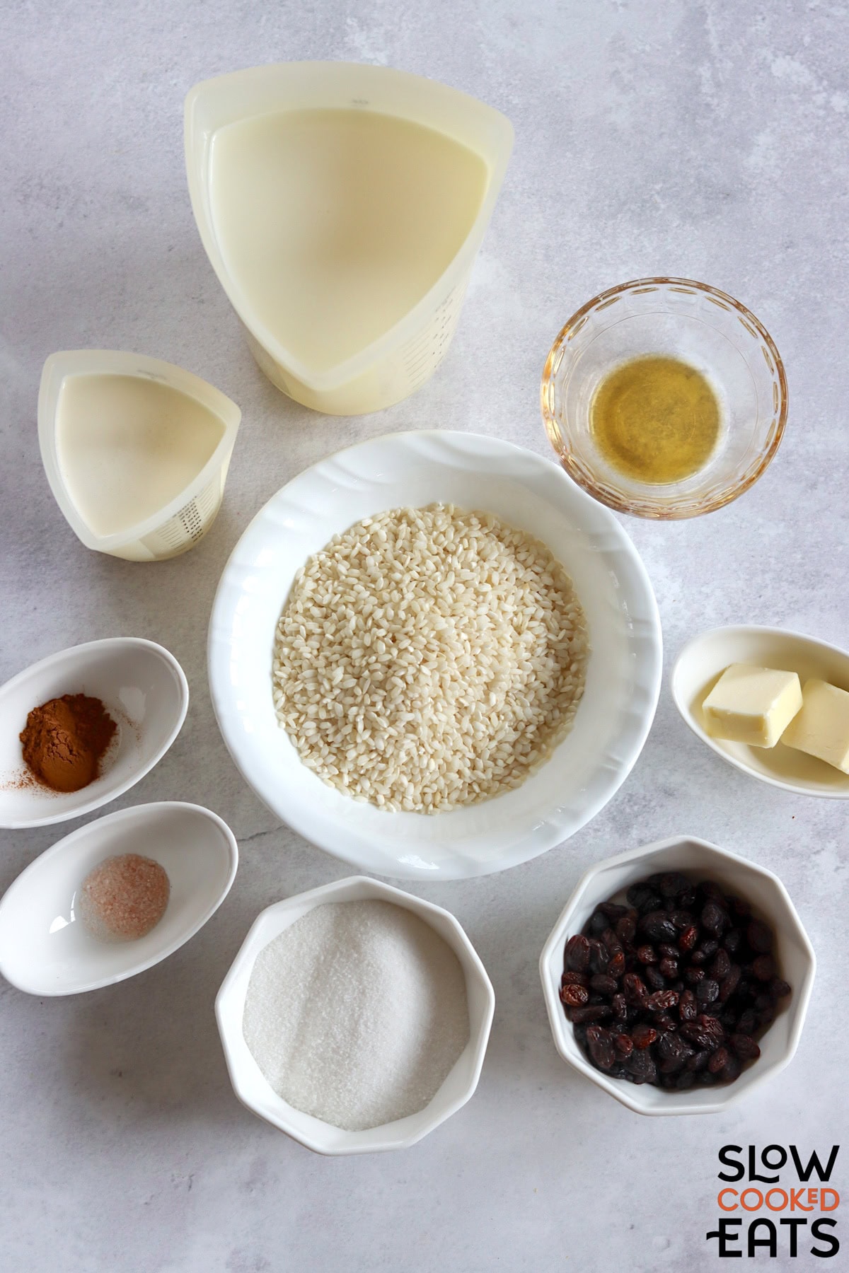 Ingredients needed to make crockpot rice pudding on a white marble countertop.
