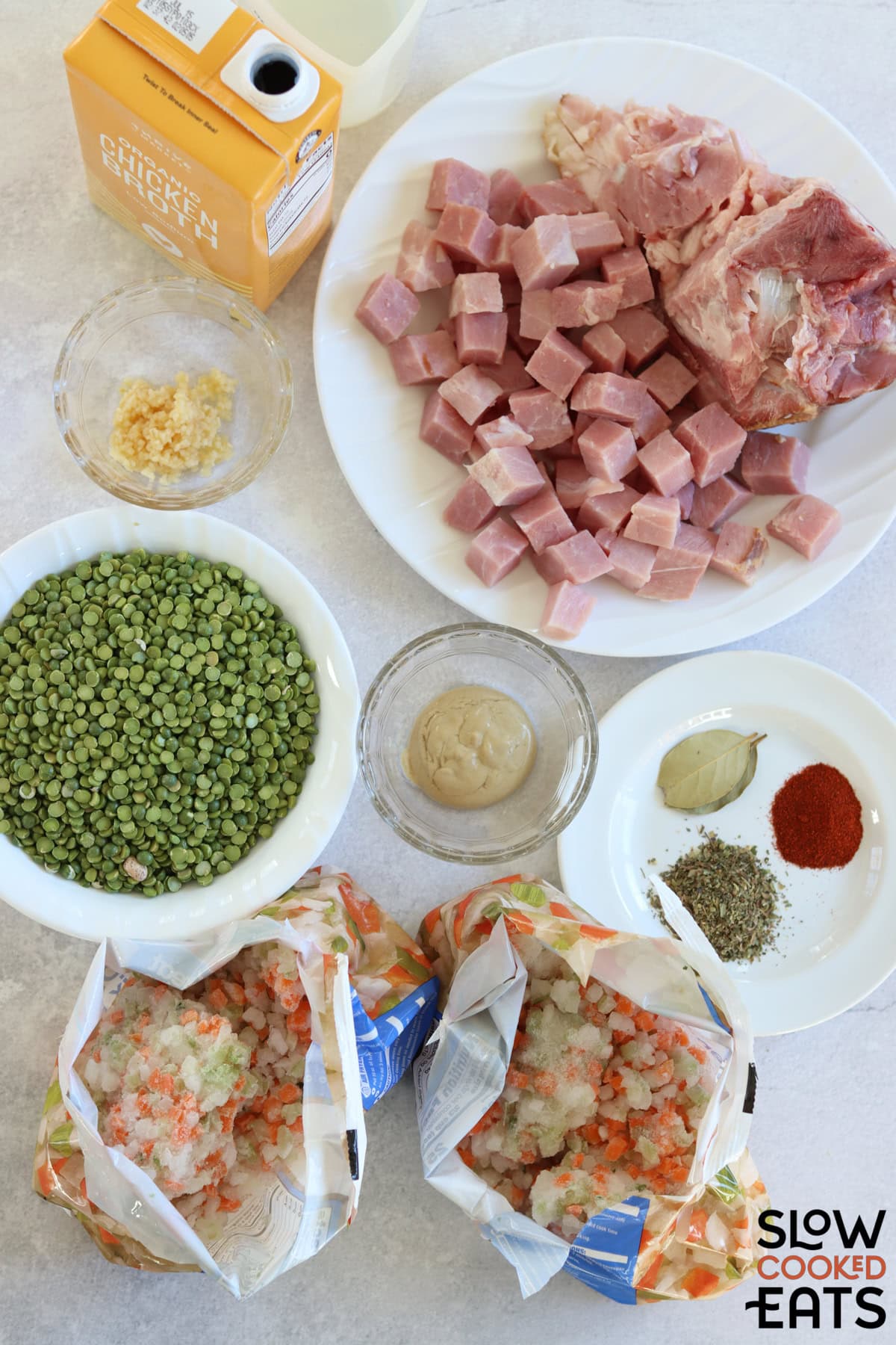 Ingredients needed to make crockpot split pea and ham soup recipe on a white marble countertop.