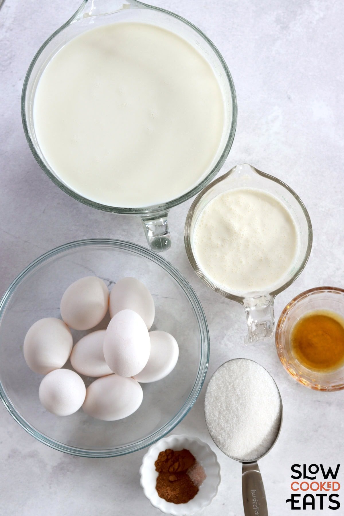 Ingredients needed to make crockpot eggnog recipe on a white marble countertop.