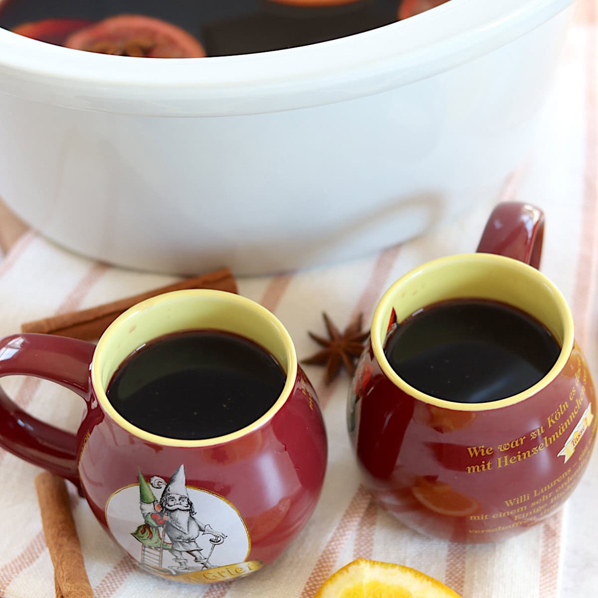 Two Red and yellow mugs filled with mulled wine recipe crockpot.