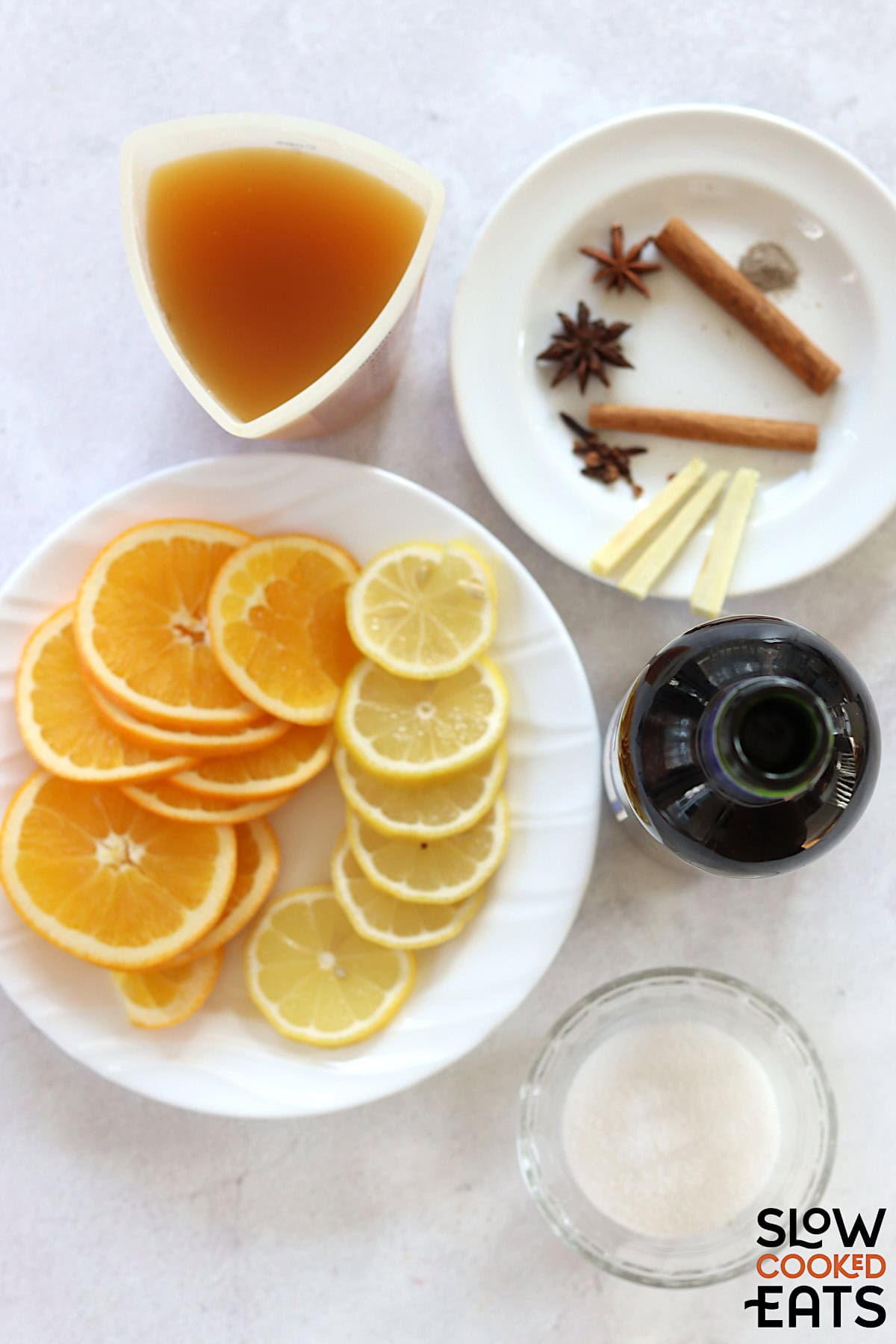 Ingredients needed to make mulled wine recipe crockpot on a white marbled countertop.