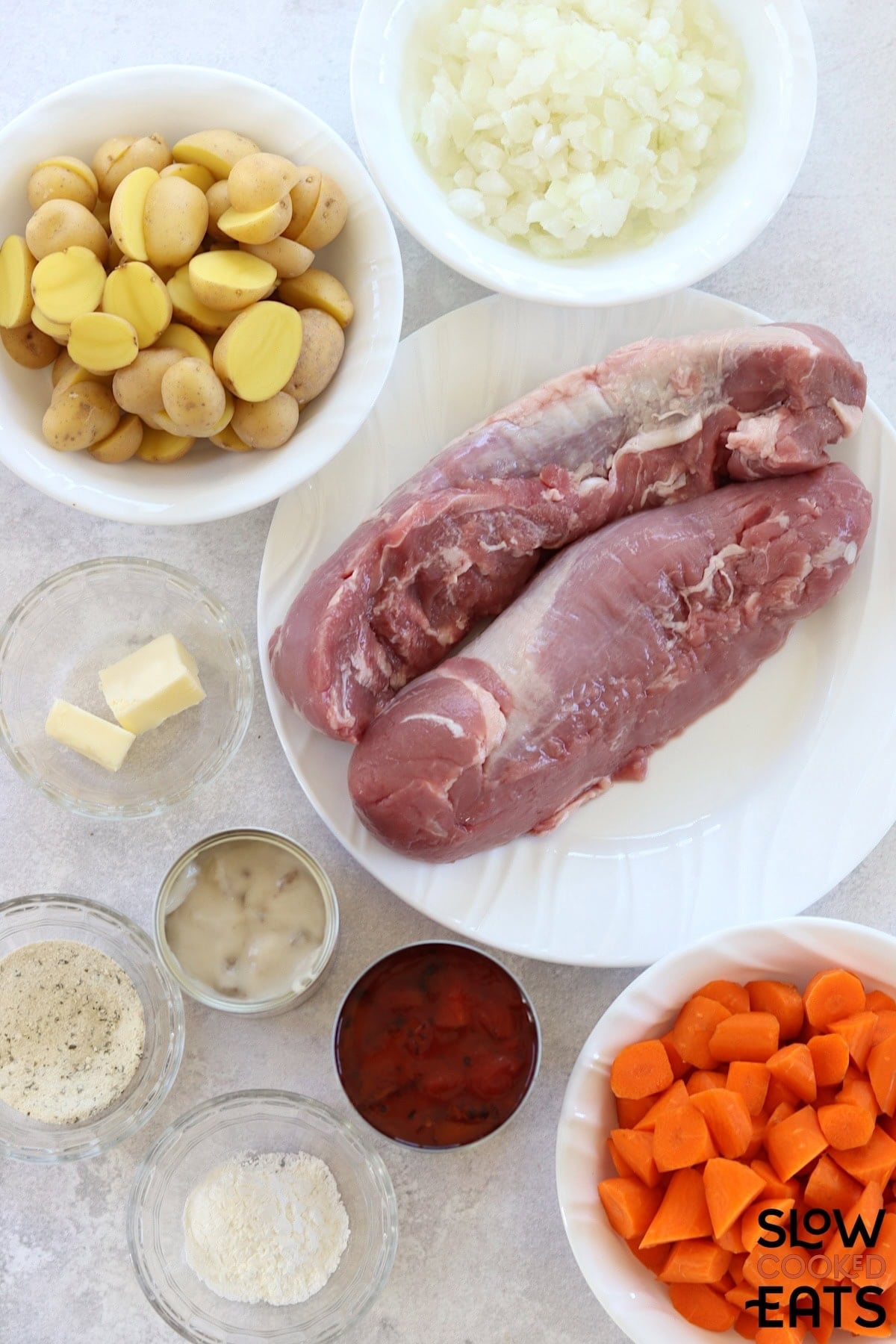 Ingredients needed to make ranch crockpot pork tenderloin with vegetables on a white marble countertop.
