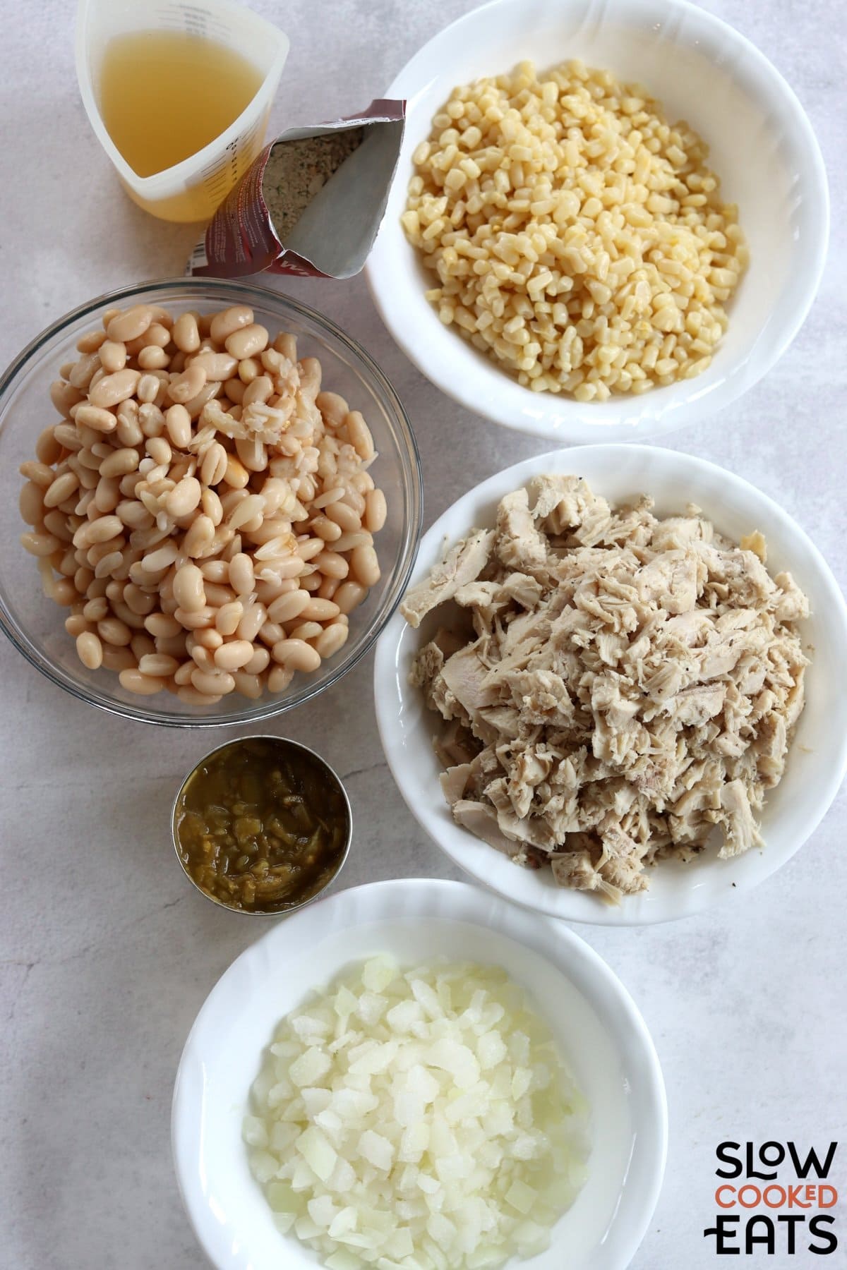 Ingredients needed to make leftover slow cooker turkey white chili on a white marble countertop.