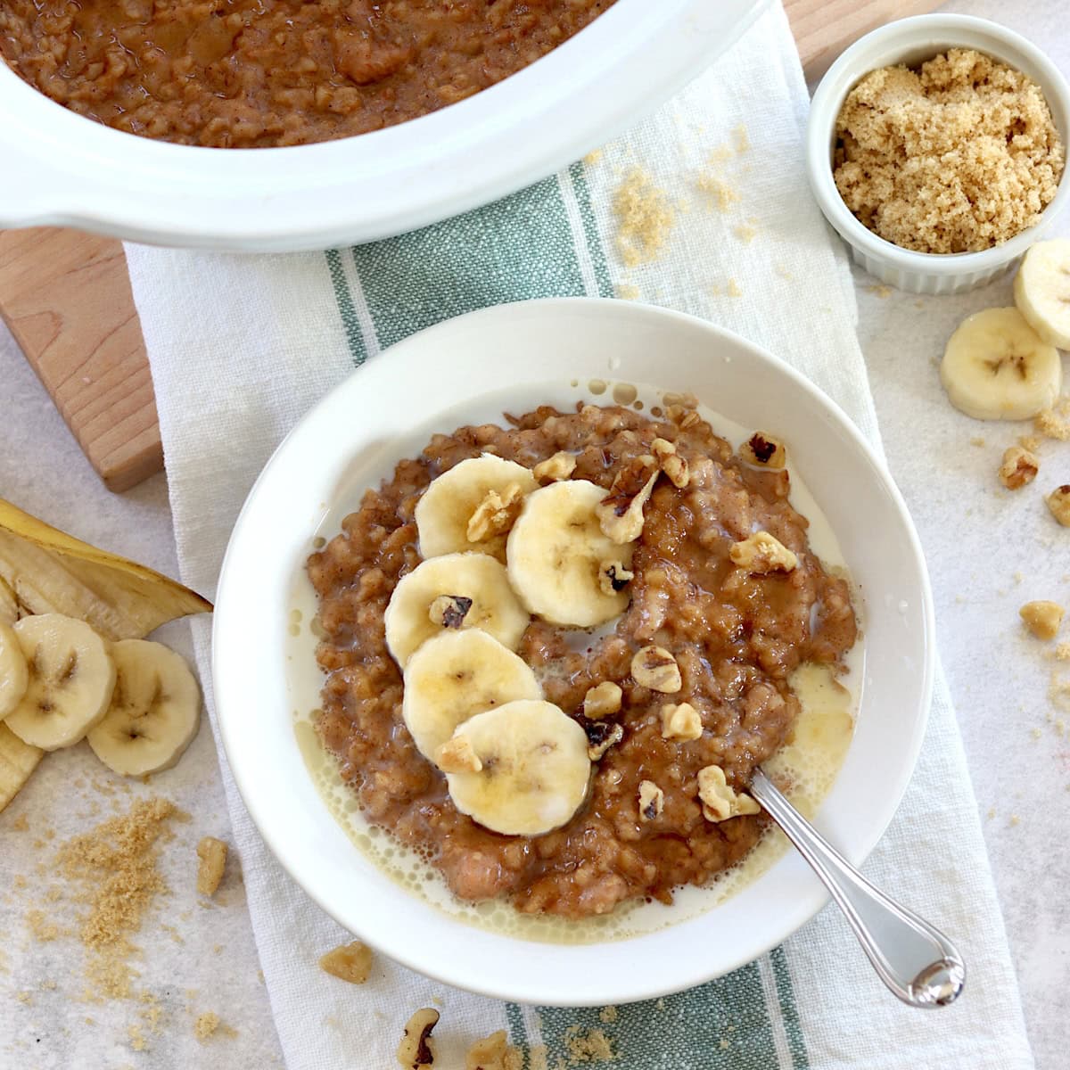 Crockpot banana oatmeal recipe served in a white round bowl and silver spoon.
