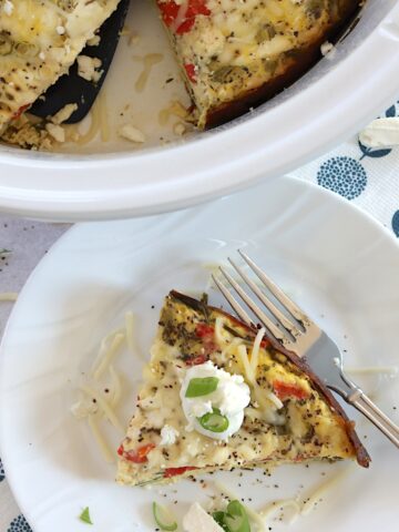 Mediterranean crockpot frittata served on a white round plate and silver fork.