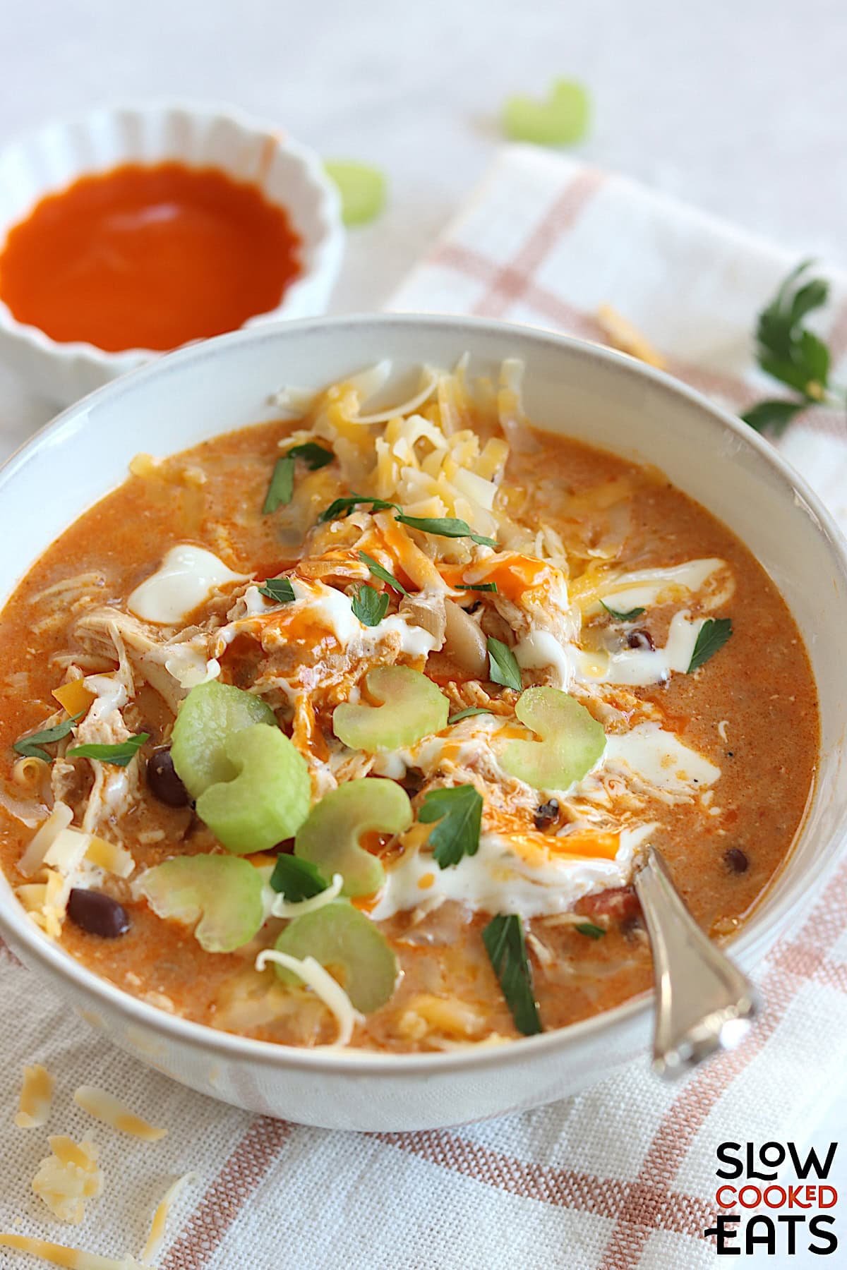 The best buffalo chicken chili crockpot recipe served in a white round bowl and silver spoon.