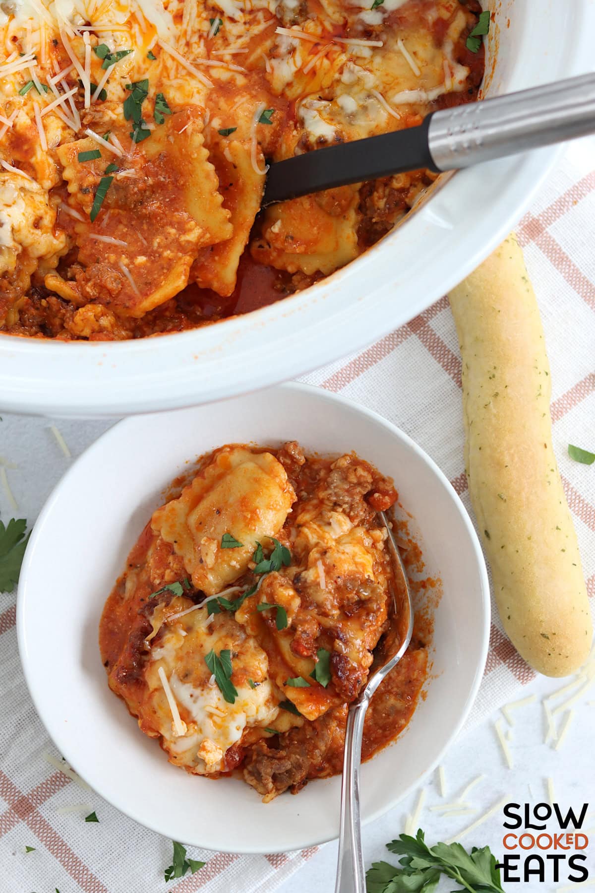 Crockpot ravioli lasagna served in a small round white bowl and silver fork.