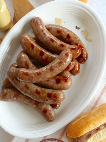 Beer brat crockpot recipe served in a stack on a white oval platter.